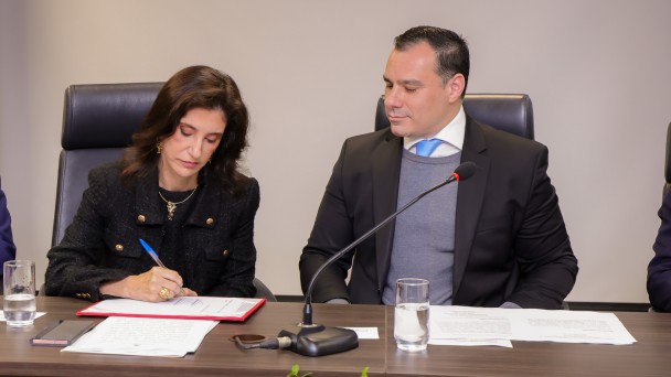 Dra Georgine assina o termo de posse na mesa de autoridades ao lado do procurador-geral do Estado.